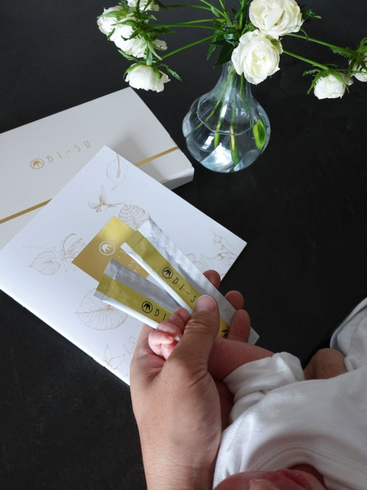 BI-SU jelly sticks held beside a baby's hand, with white roses