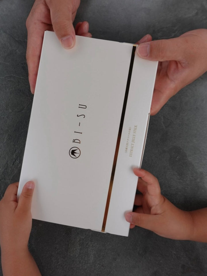 A family's hands passing a box of BI-SU as a gift